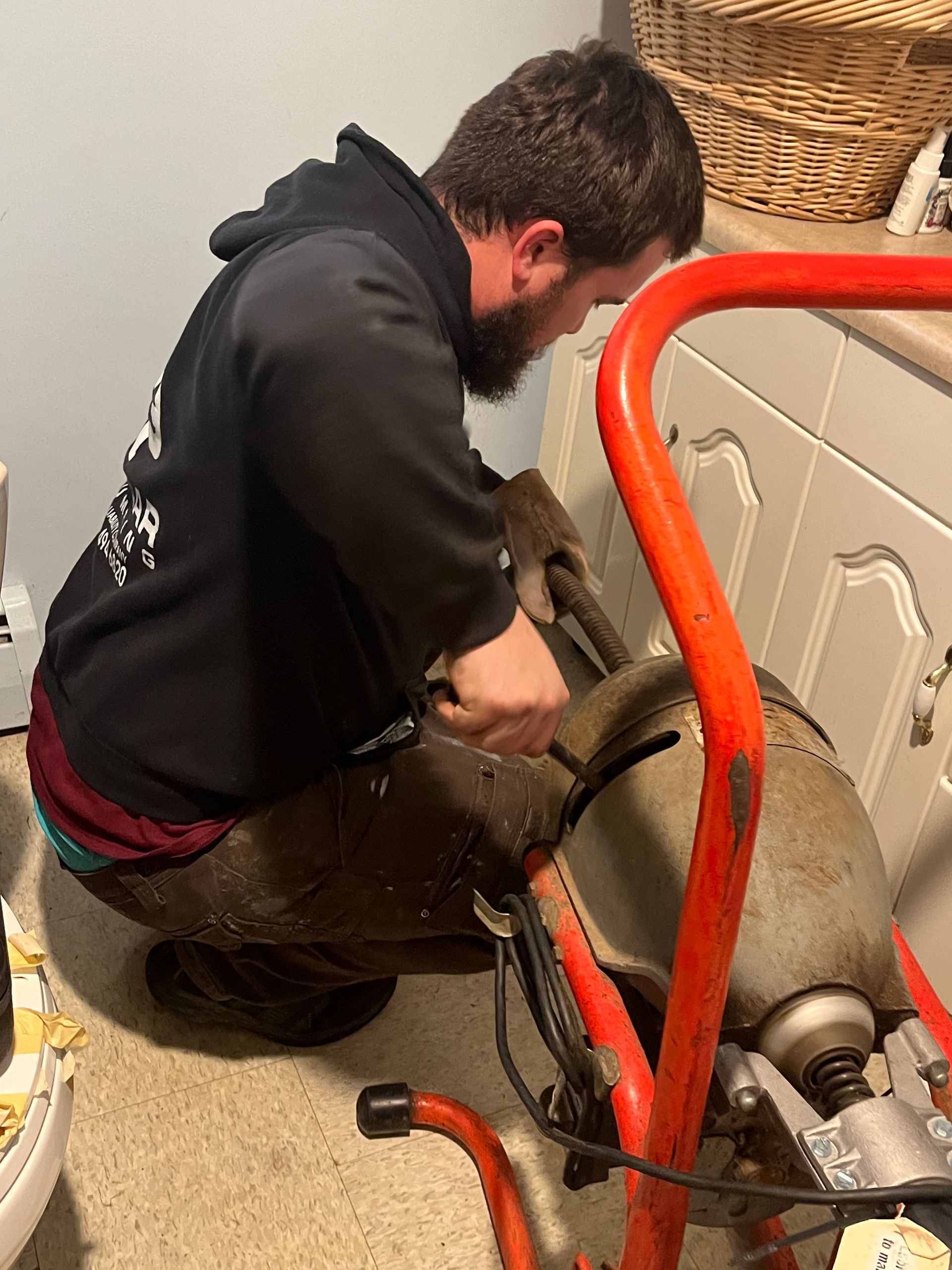 a man is kneeling down in front of a machine in a bathroom .