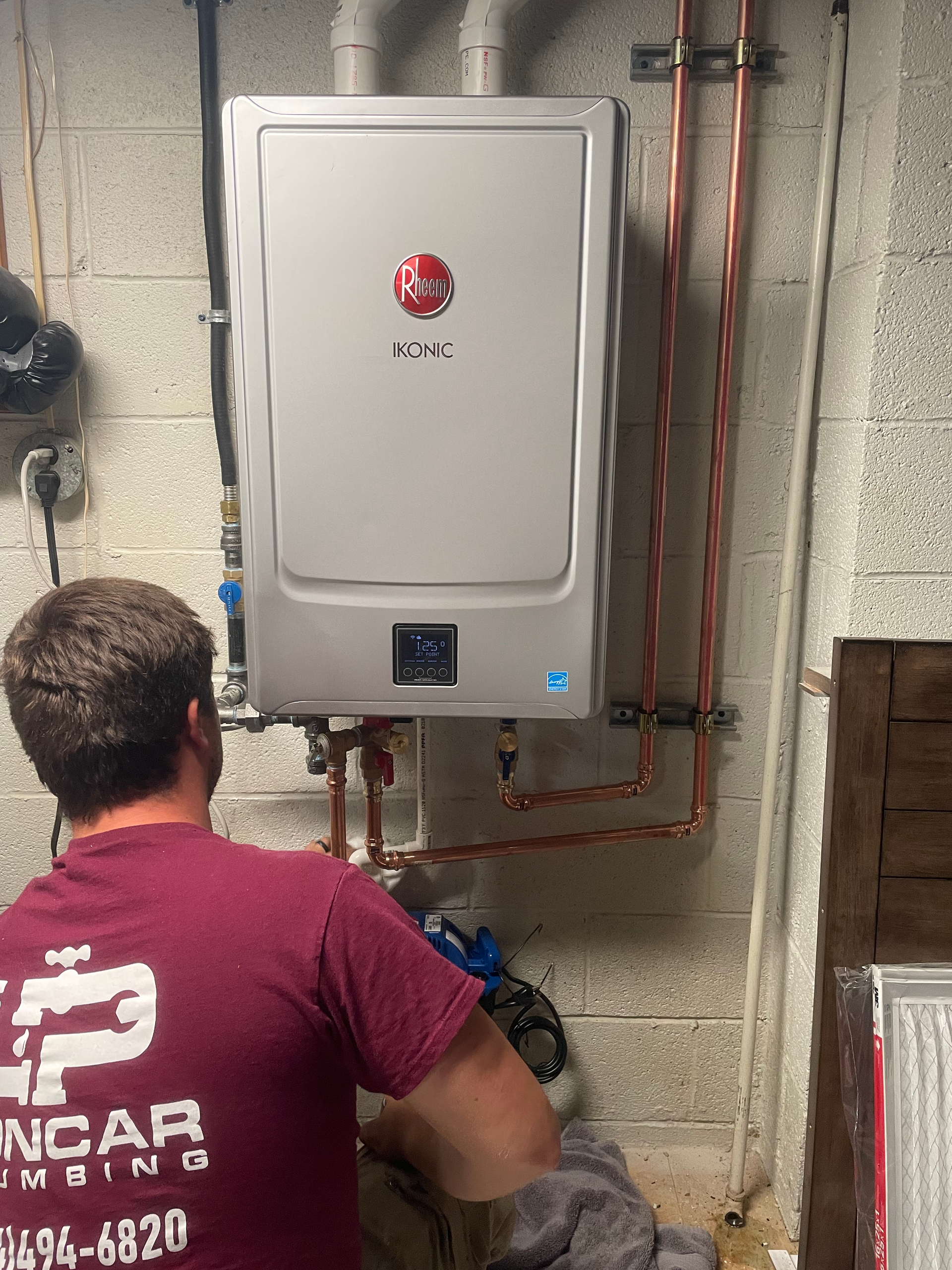a man in a red shirt is working on a water heater .