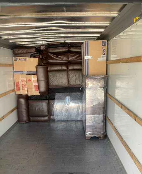 Packed moving truck interior with stacked boxes, wrapped furniture, and a small open floor area