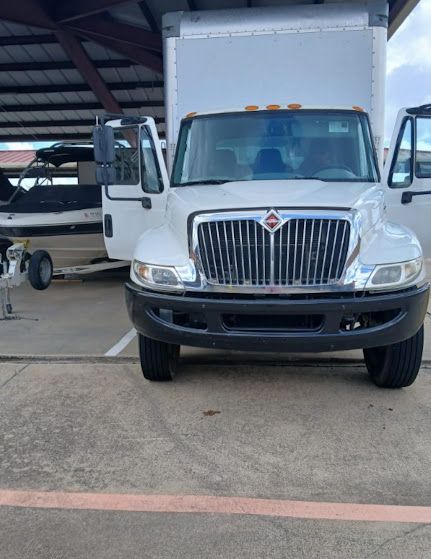 White box truck parked under a covered loading area, front view with both doors open