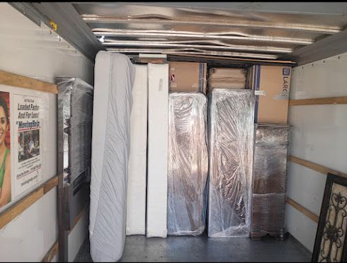 Packed moving truck interior with wrapped mattresses, boxes, and furniture secured for transport