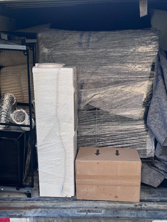 Stacked cardboard boxes and wrapped pallets stored in a warehouse shelving area.