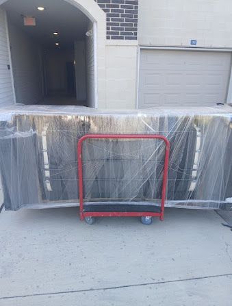 Red cart in front of a plastic-wrapped pallet blocking a garage driveway