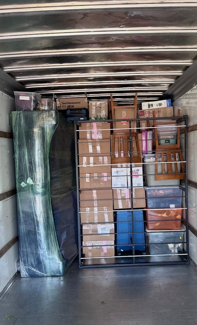 Packed moving truck with stacked cardboard boxes and wrapped furniture inside