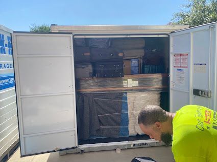 Open storage container with stacked boxes; worker in neon shirt bends in foreground