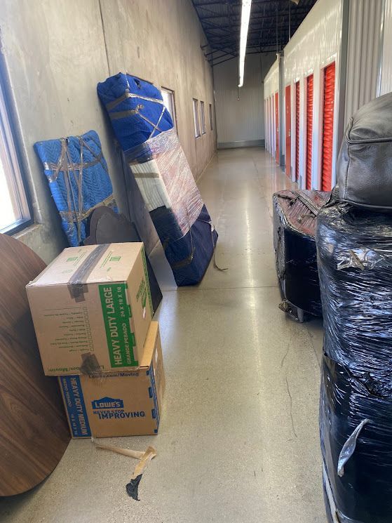 Narrow storage hallway with stacked boxes and wrapped furniture along the walls