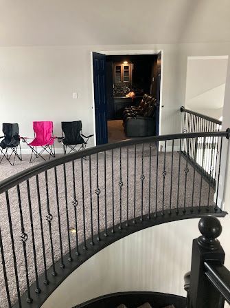 Indoor balcony hallway with three folding chairs and an open doorway