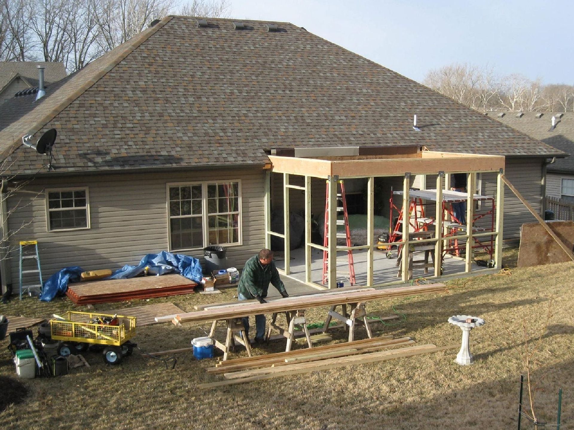 A Man Is Working on A Wooden Structure in Front of A House — Columbia, MO — Naugle Construction Company