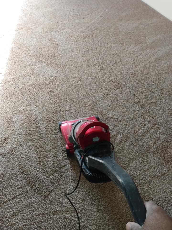 Red vacuum cleaner on a beige carpet with a cord trailing beside it.