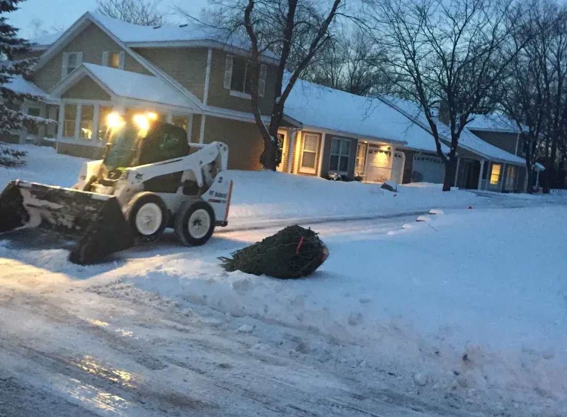 A snow blower is clearing snow in front of a house