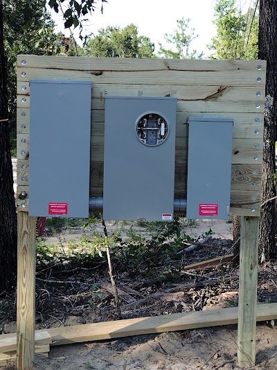 Three electrical boxes are sitting on top of a wooden fence.