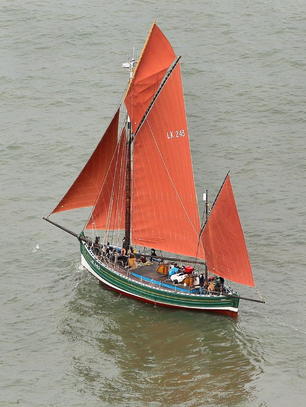 A boat with red sails is floating on the water