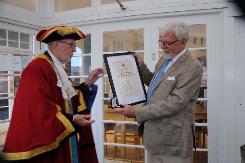 A man in a red robe is giving another man a certificate