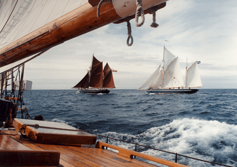 Sailing ships race across the sea generating a wake and excitement