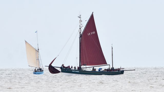 A boat with a red sail is floating in the sea