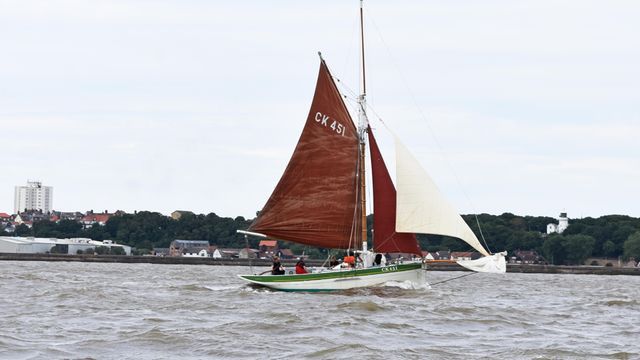 A sailboat with a red sail is floating on top of a body of water.