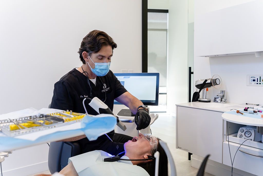 Dentist treating a patient in a bright clinic, with dental tools and monitor nearby.
