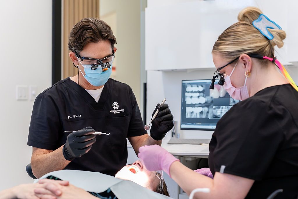 Dentists in masks and gloves treating a patient in a dental clinic