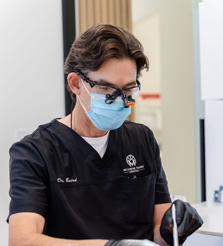 Dentist in black scrubs and mask working with dental tools in a clinic