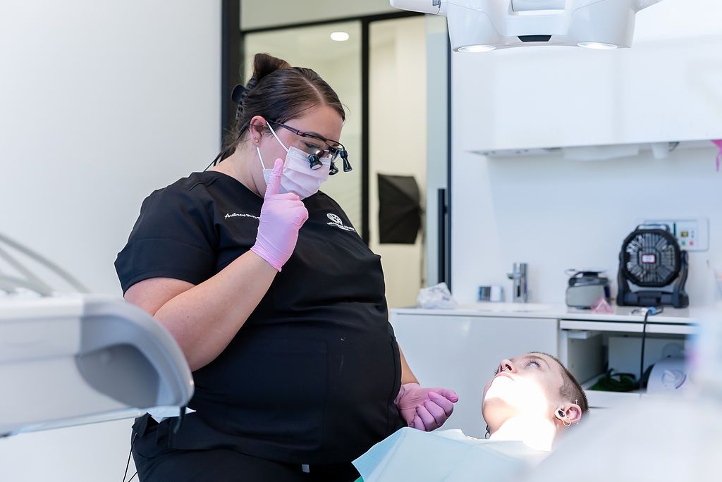 Dentist in black uniform and mask examining a patient