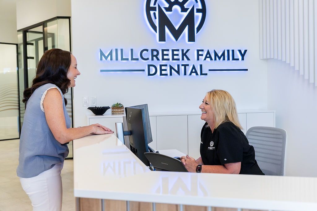 Reception desk at Millcreek Family Dental with two people talking in a bright office