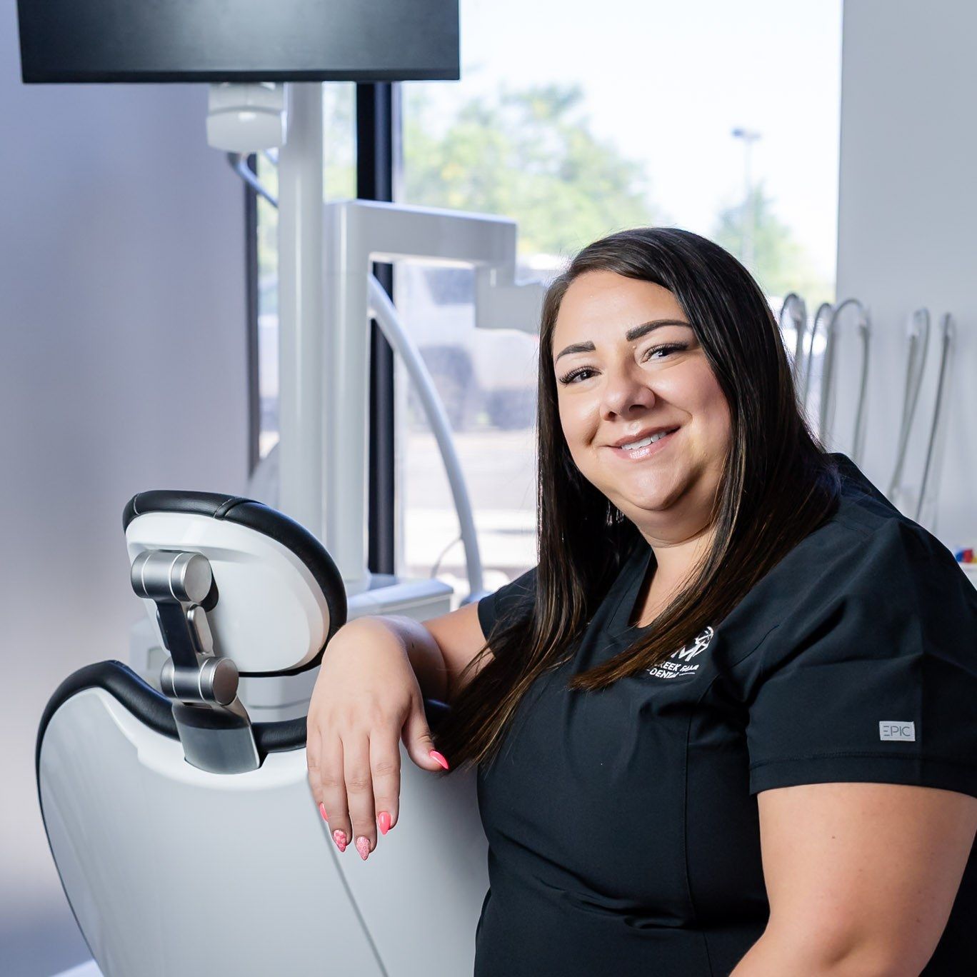 Smiling Millcreek Family Dental team member seated in a dental chair, Bountiful