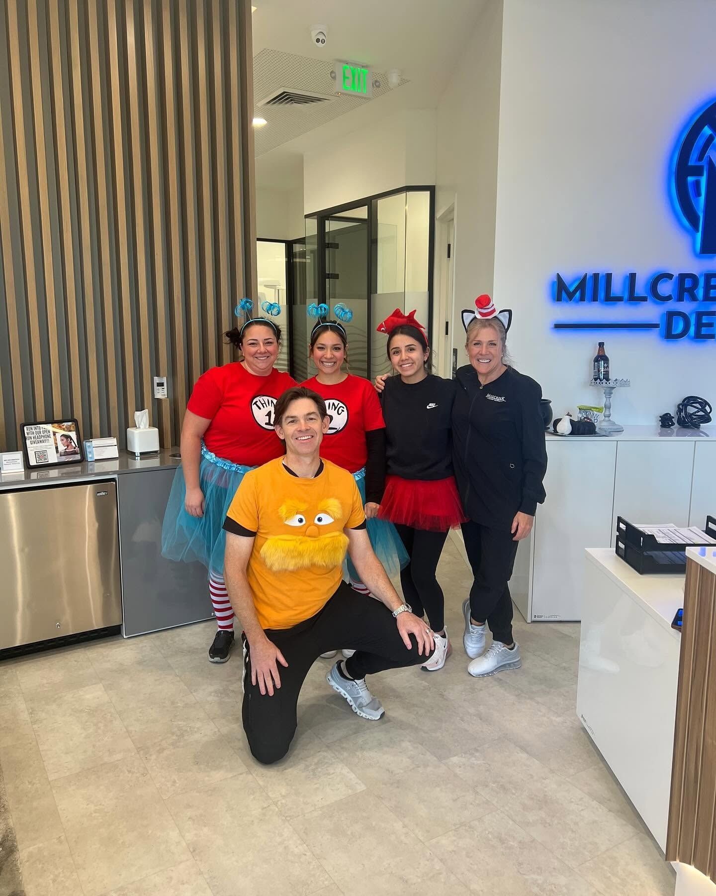 Five people posing together in a bright office lobby