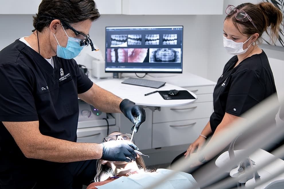Dentist and dental assistant performing a restorative dental procedure on a patient