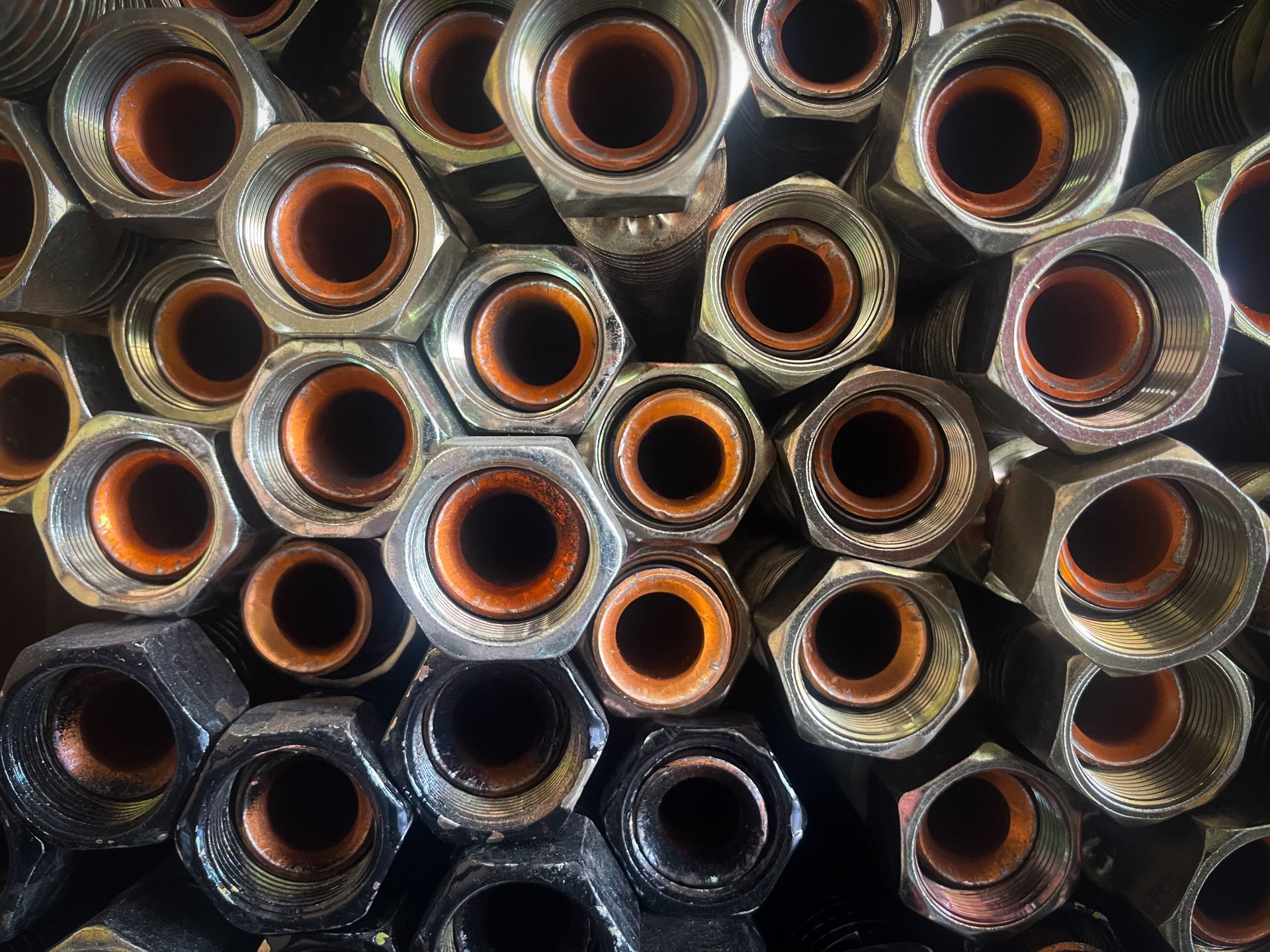 Top view of high-pressure hydraulic hose fittings with internal seals and hexagonal metal nuts.