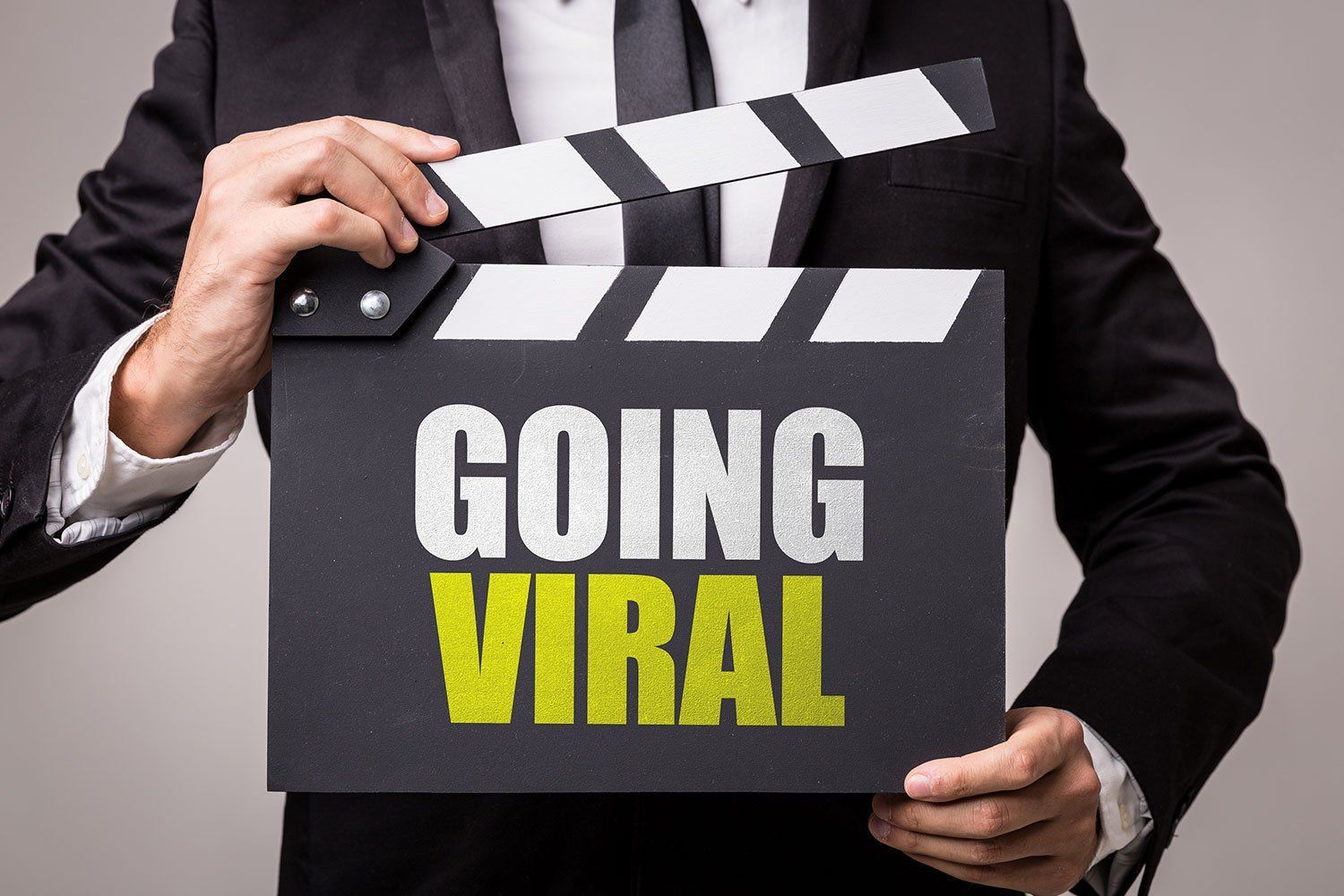 A man in a suit is holding a clapper board that says going viral