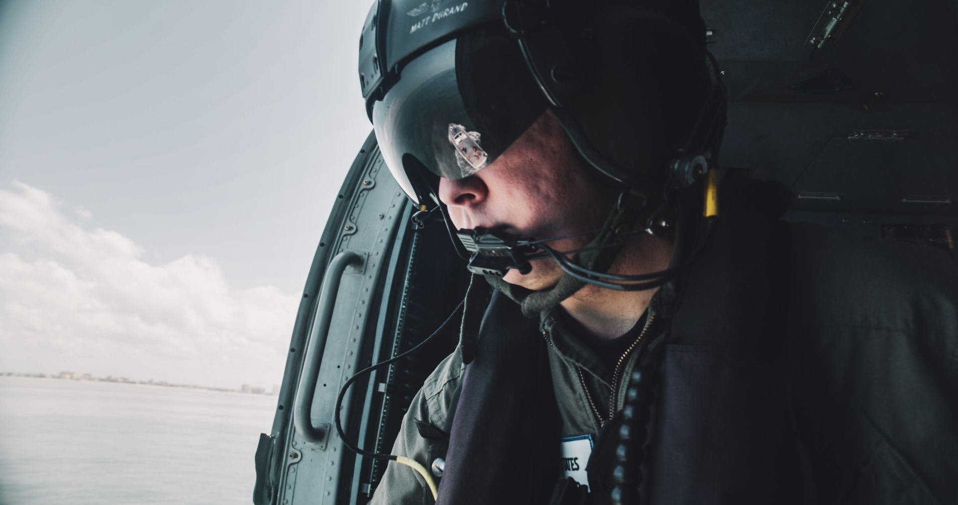 A man wearing a helmet and goggles is sitting in a helicopter.