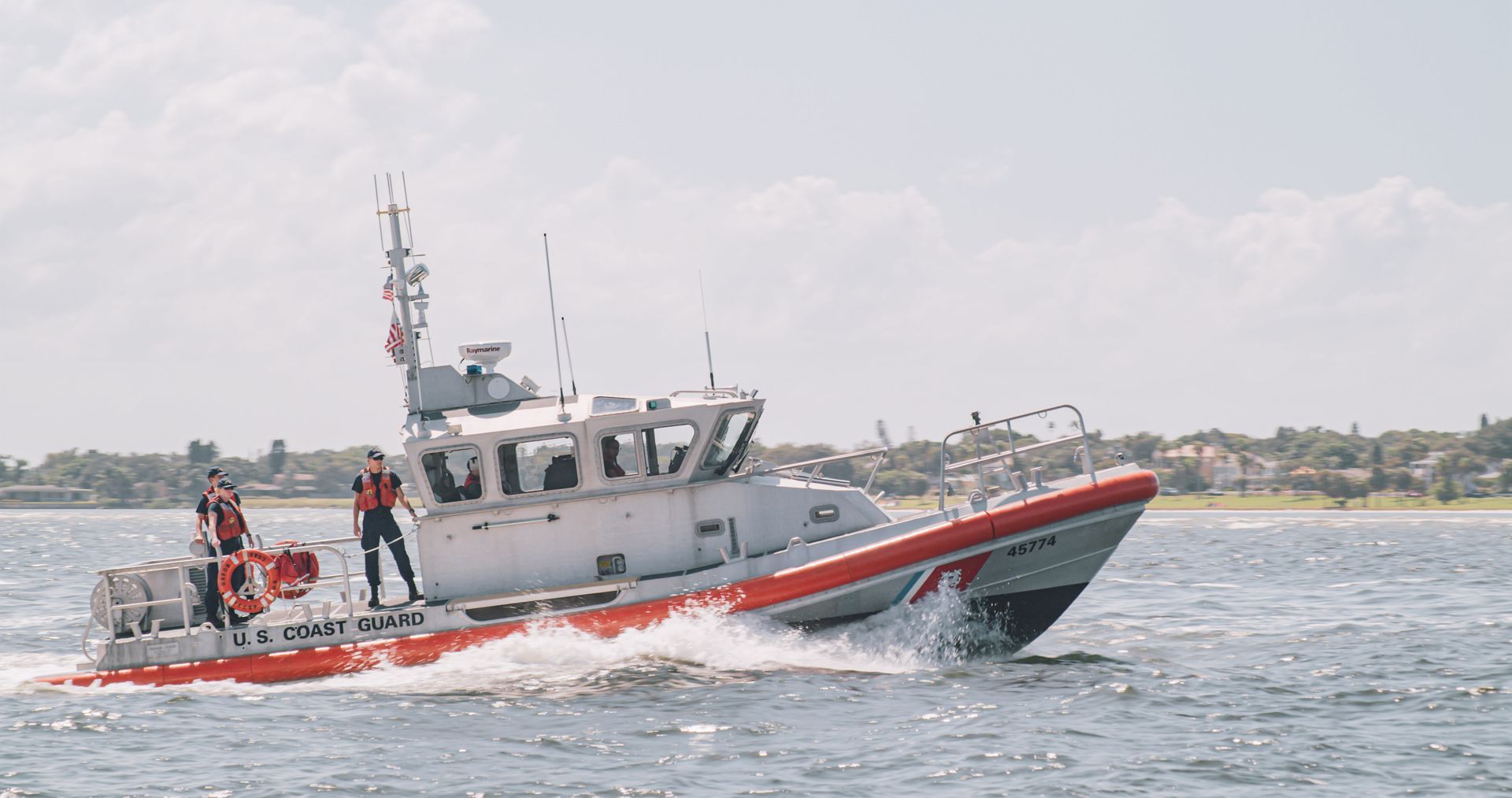 A red and white boat is floating on top of a body of water.