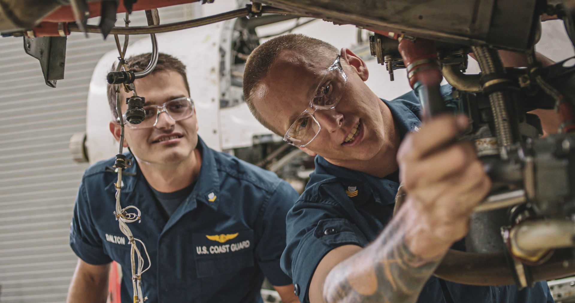 Two men are working on a plane in a hangar.