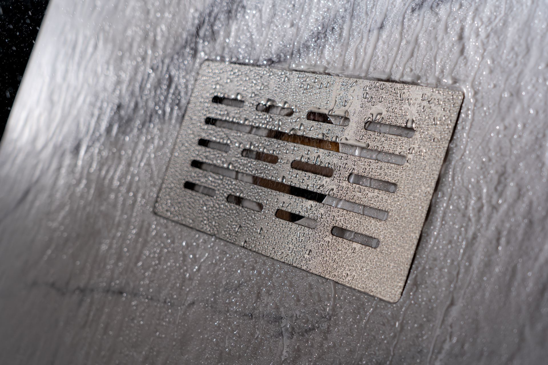 A close up of a drain on a shower stall.