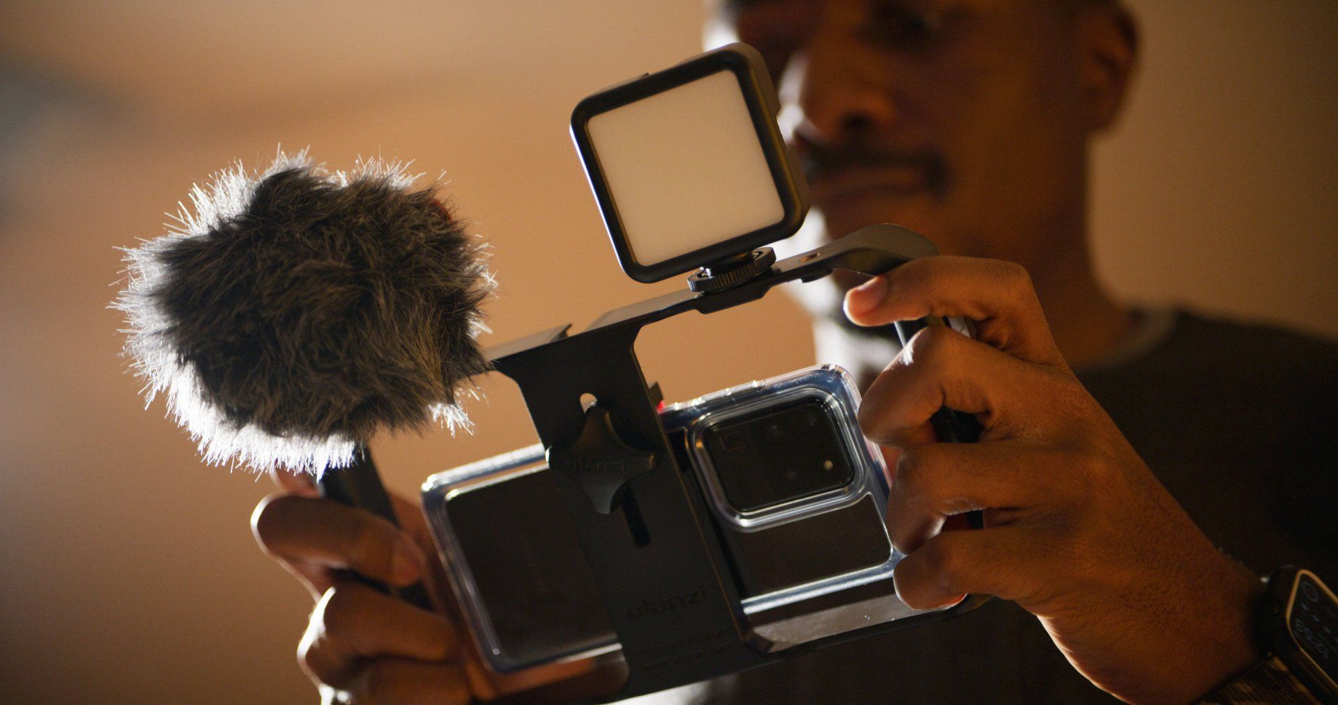 A man is holding a cell phone with a microphone attached to it.