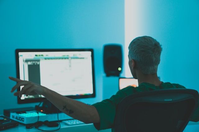 A person working in a music studio, producing and editing music using professional sound equipment.
