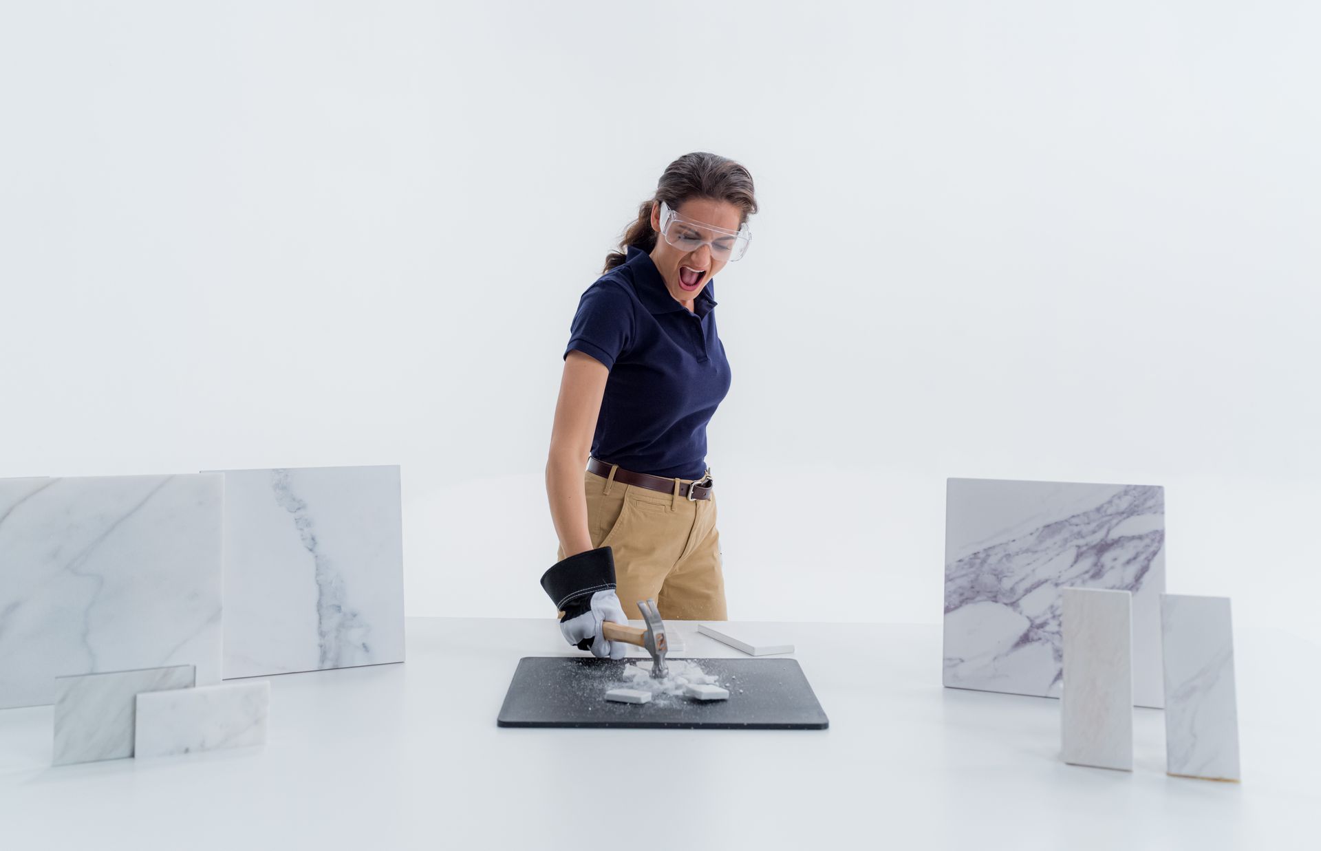 A woman is cutting a piece of marble with a saw.