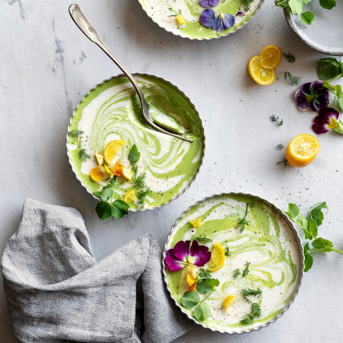 Three bowls of soup with flowers and lemons on a table
