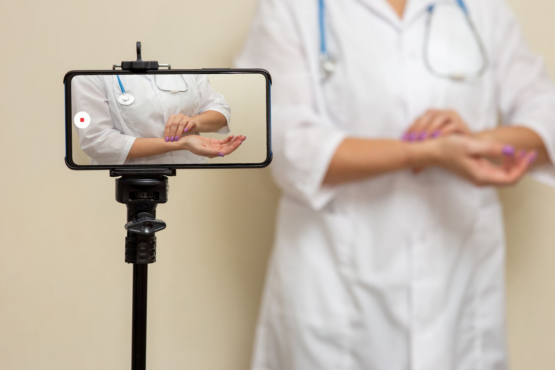 A doctor is taking a picture of herself on a cell phone.