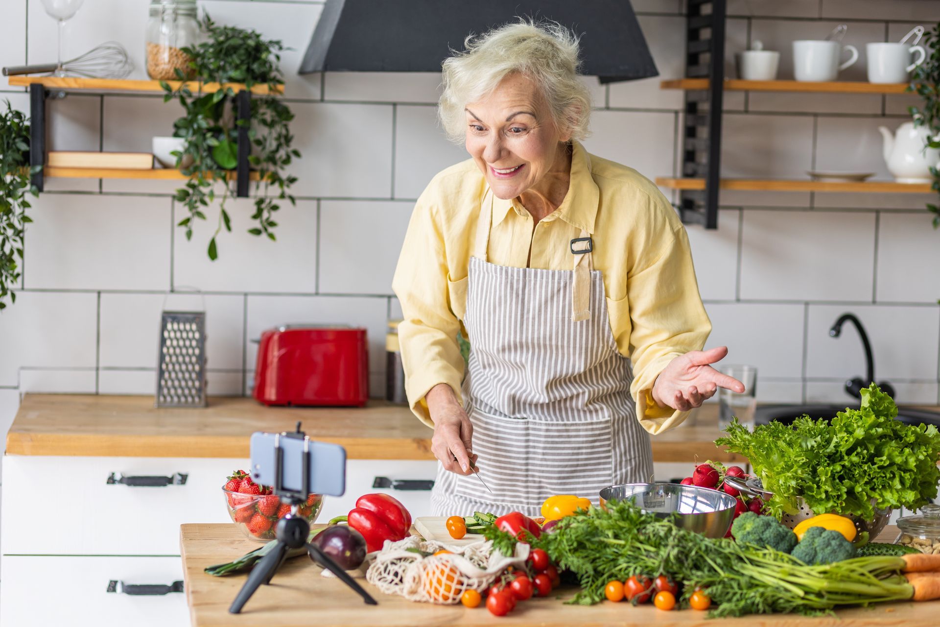 An elderly woman is standing in a kitchen preparing food.