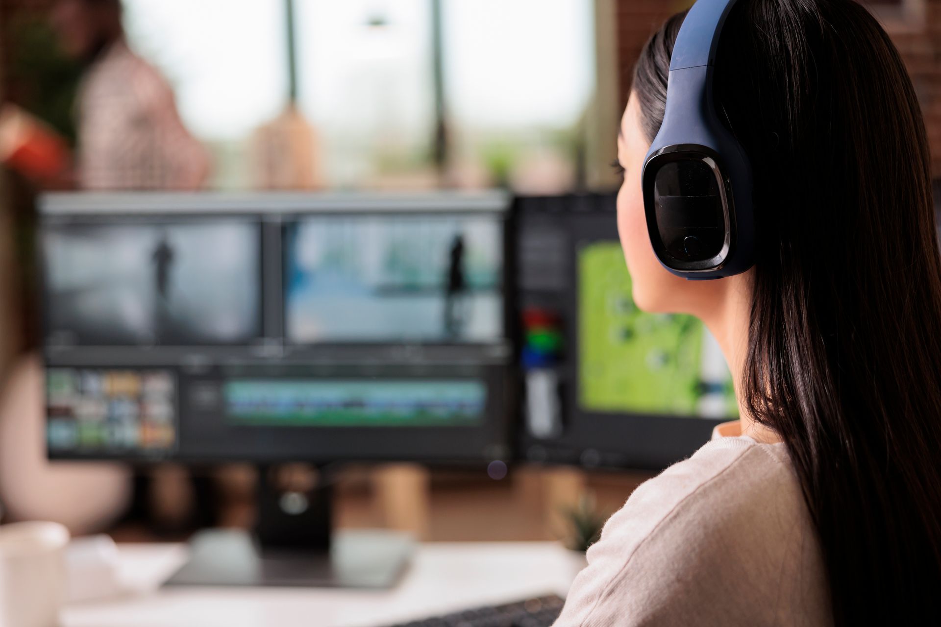 A woman wearing headphones is sitting in front of a computer screen.