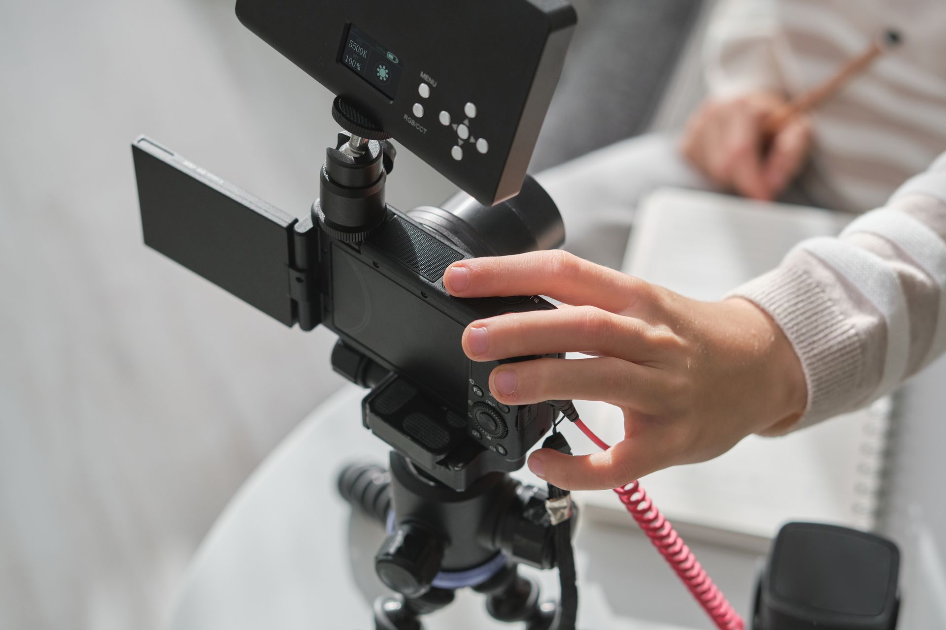 A person is holding a camera on a tripod.