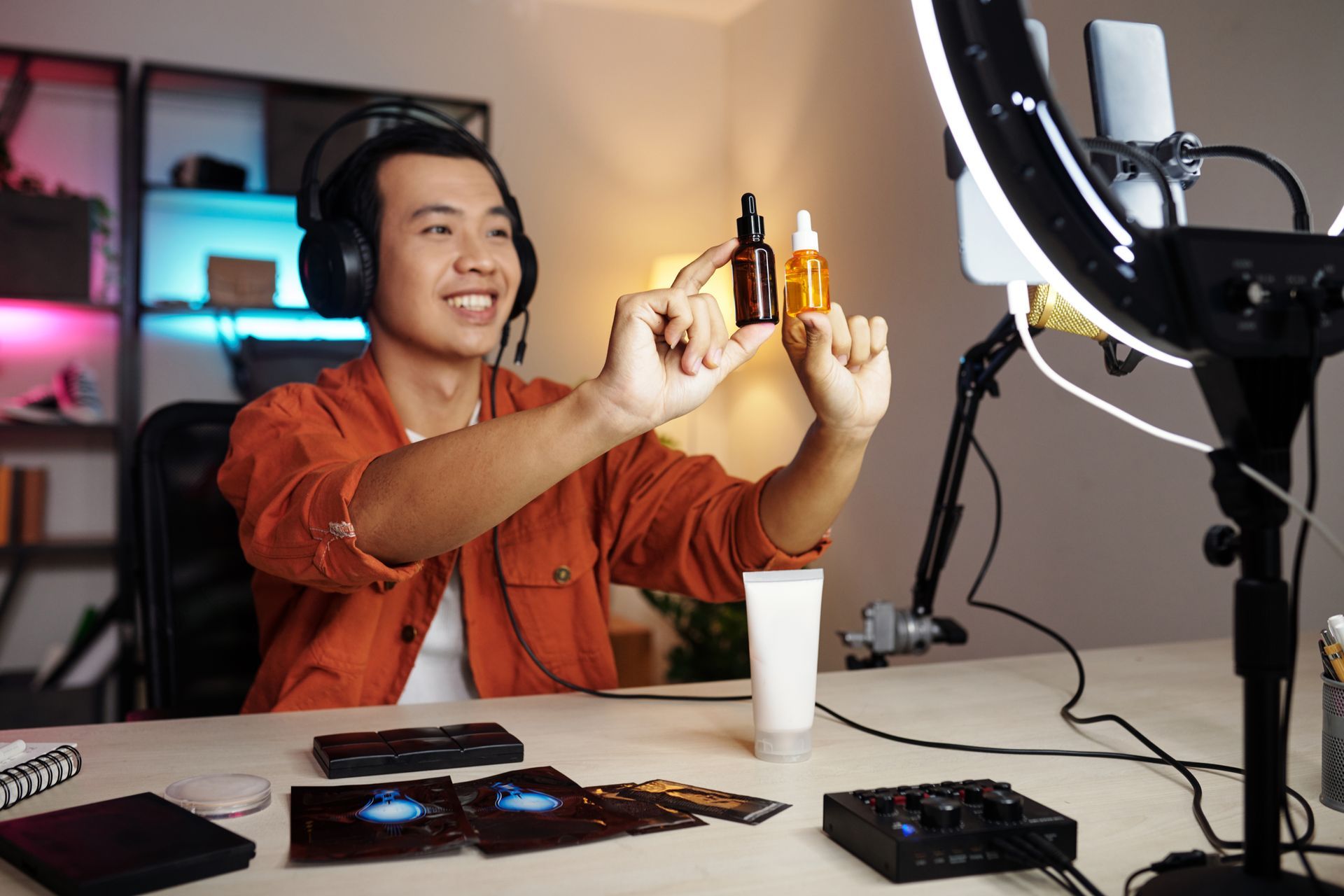 A man wearing headphones is holding a bottle of lotion in front of a microphone.