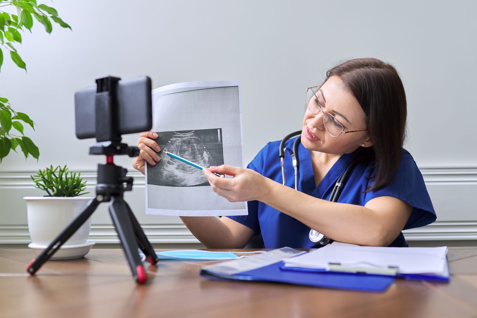 A female doctor is holding a picture of an ultrasound and pointing at it.