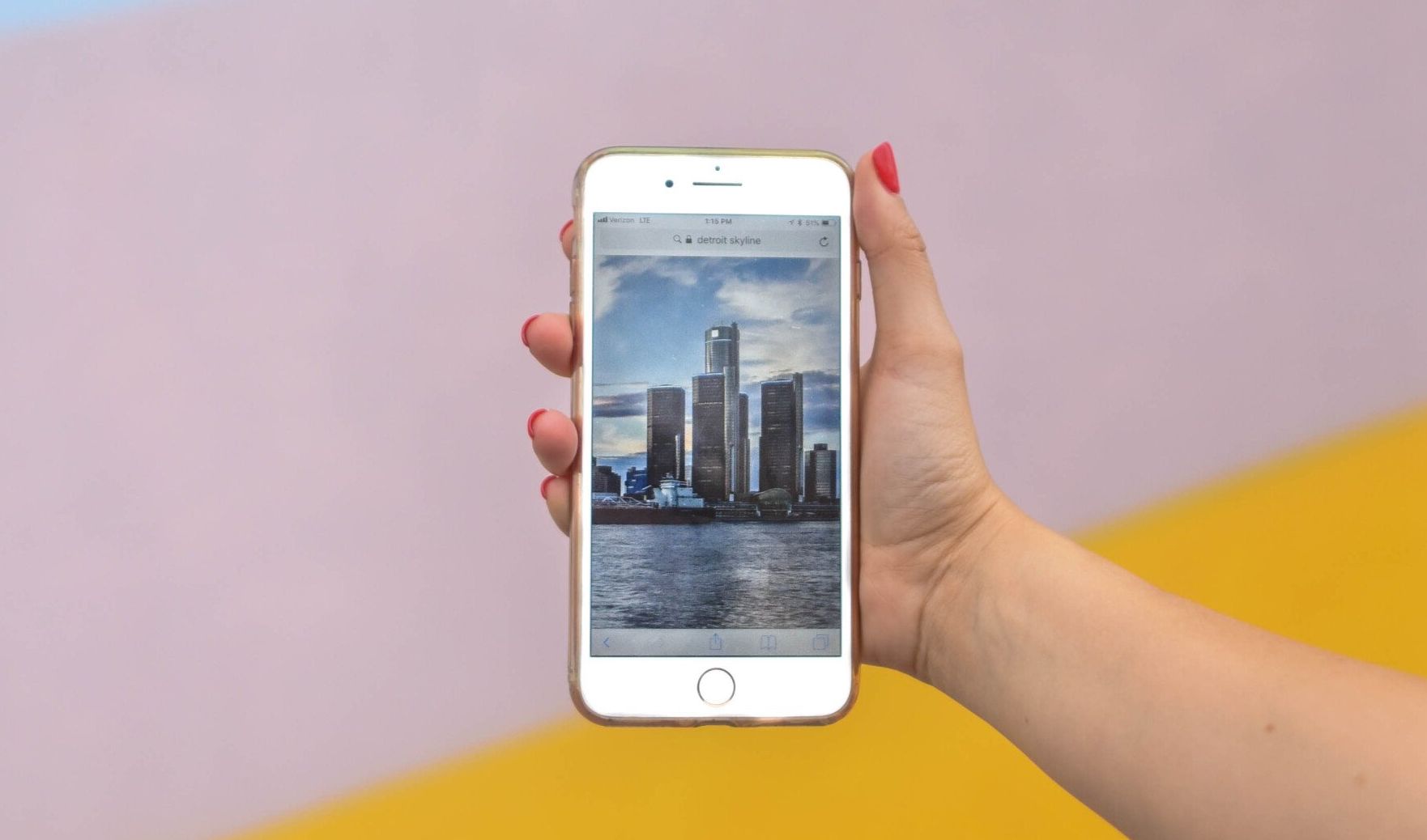 A person is holding a cell phone with a picture of a city skyline on the screen.
