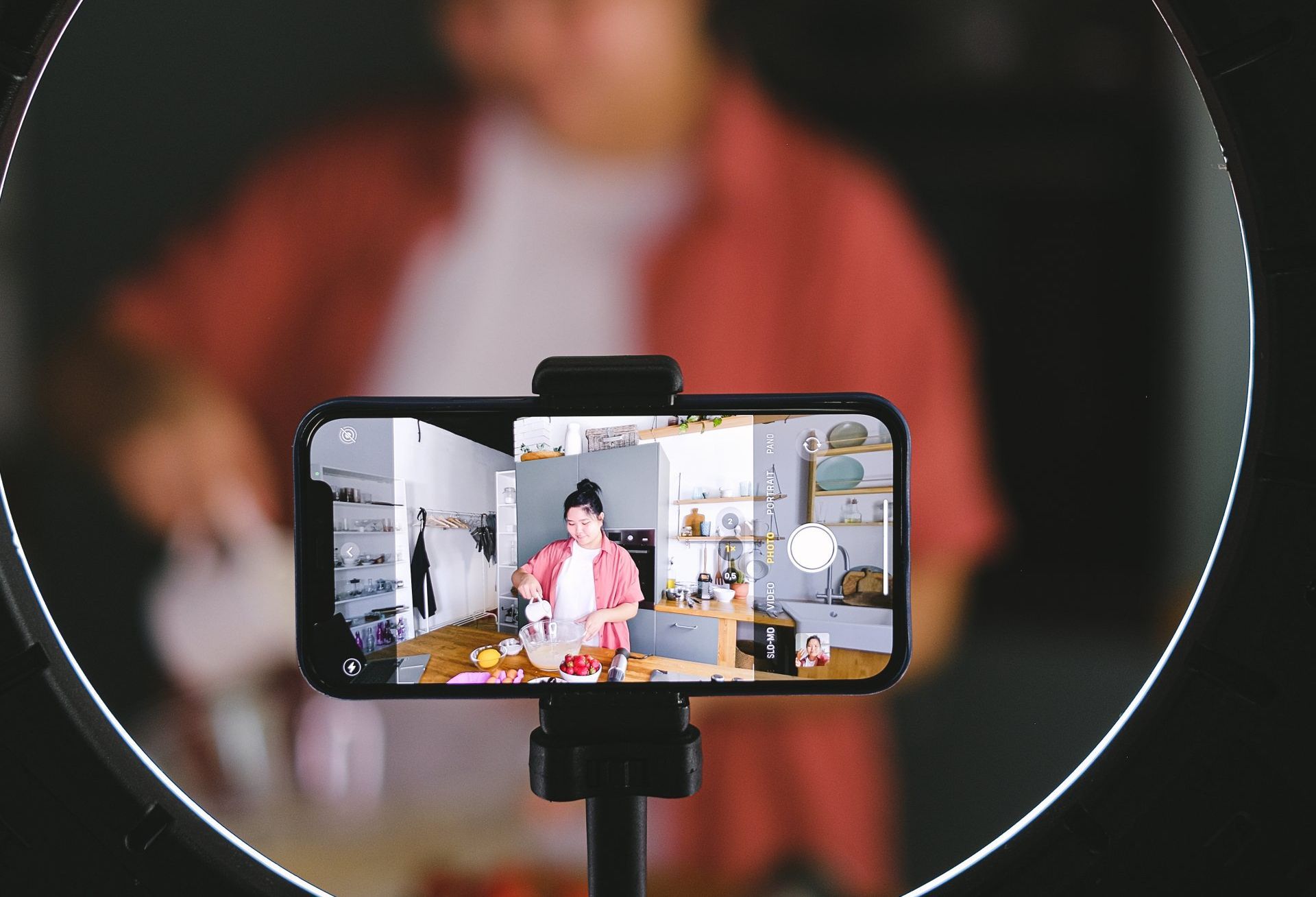 A person is recording a video on a cell phone with a ring light.