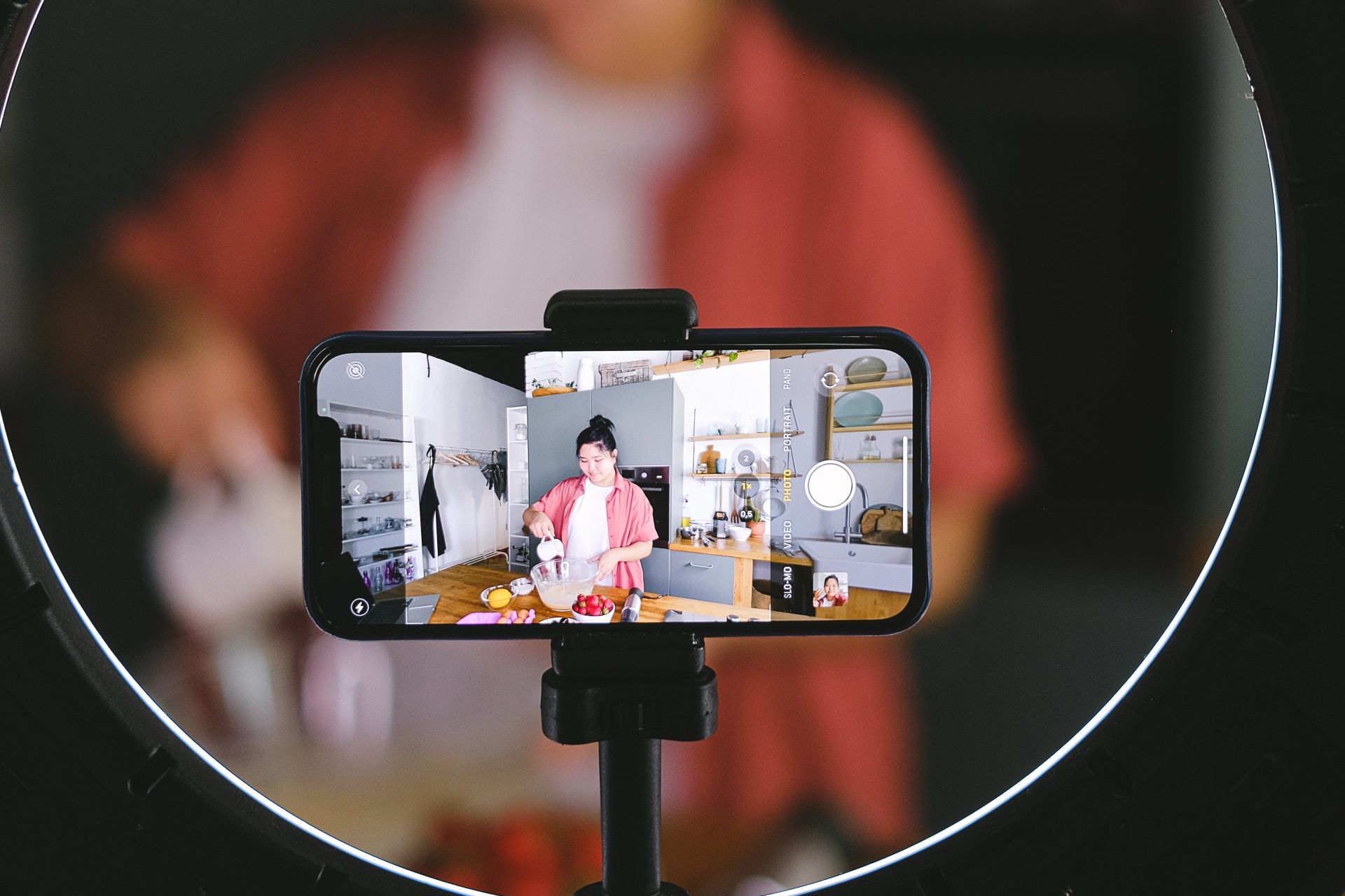 A person is recording a video on a cell phone with a ring light.