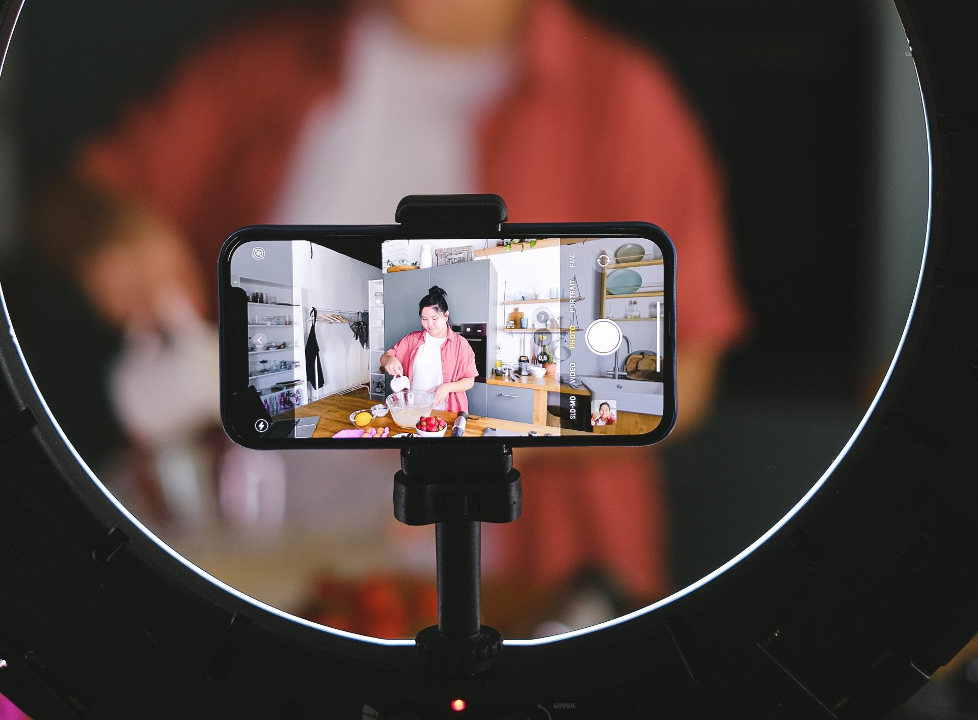 A person is recording a video on a cell phone with a ring light.