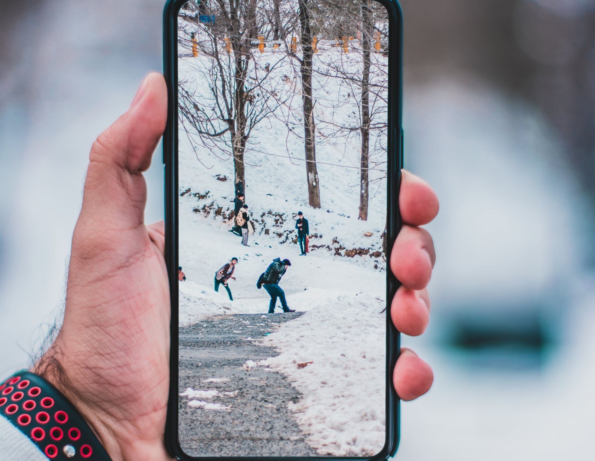 A person is holding a cell phone with a picture of people playing in the snow