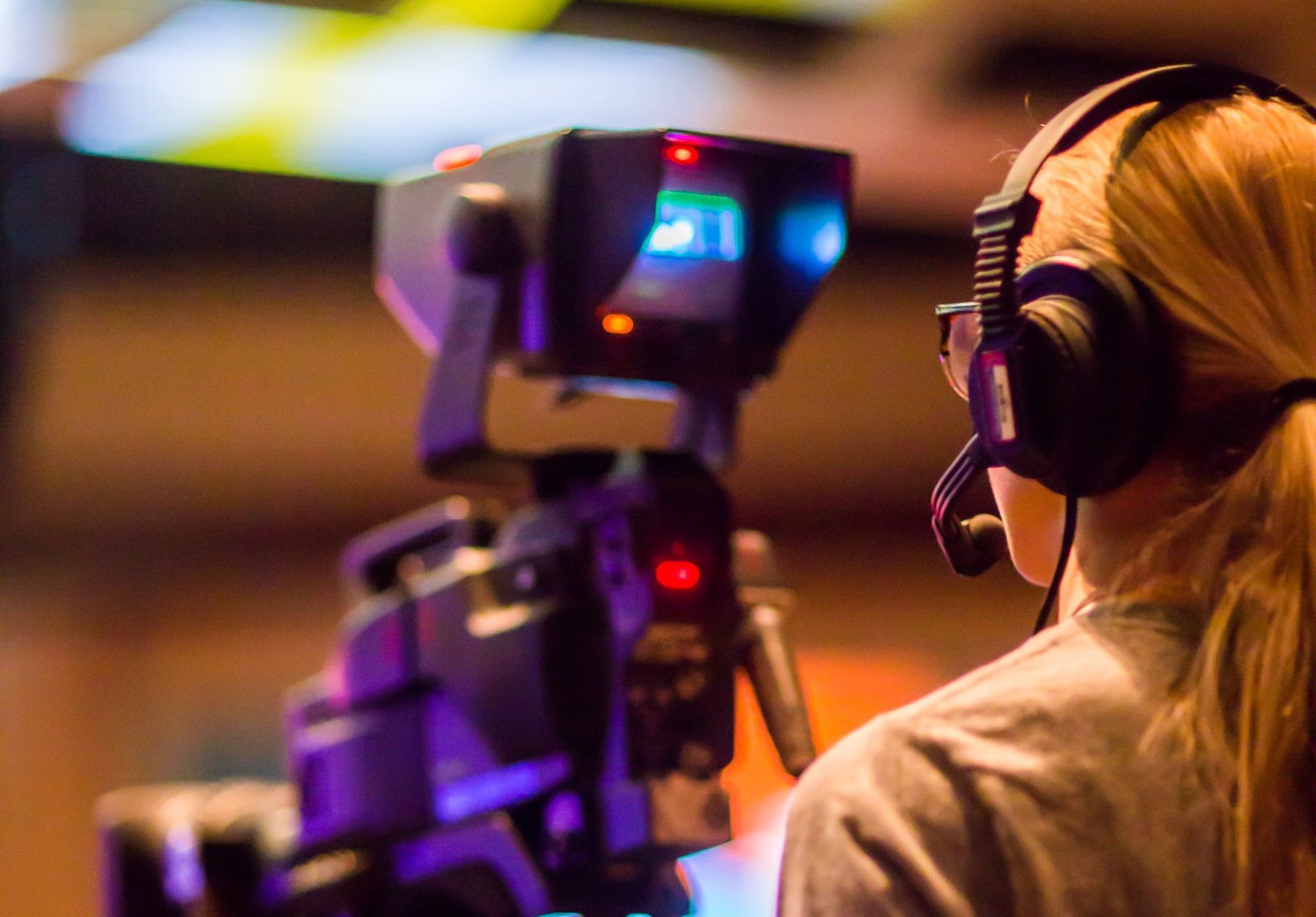 A woman wearing headphones is looking at a camera.